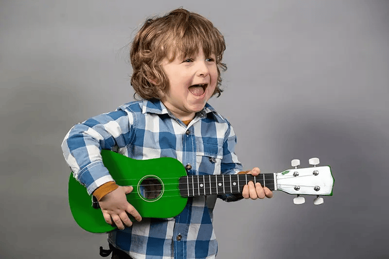 child with a
			smile holding a guitar