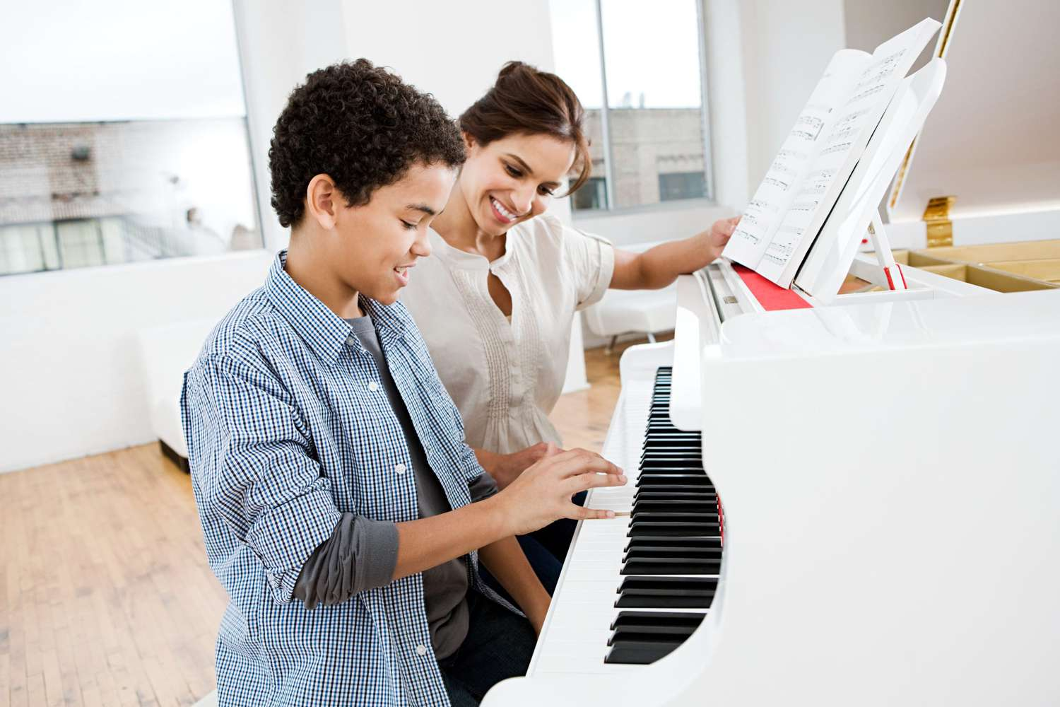 piano teacher and student sitting at a piano